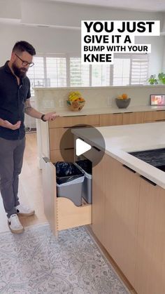 a man standing in front of a kitchen counter with an open sink and trash can