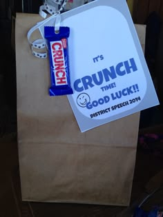 a brown paper bag with a blue and white sticker on it that says crunch time good luck