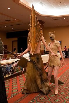 two people dressed in costumes standing next to each other on a carpeted area with tables and chairs