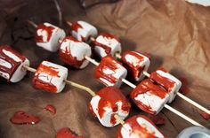 marshmallows covered in red and white icing sitting on top of brown paper