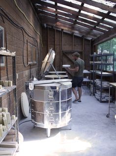 a man standing next to a large metal barrel in a room filled with shelves and tables