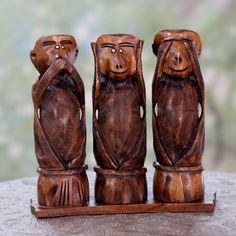 three carved wooden figurines sitting on top of a rock