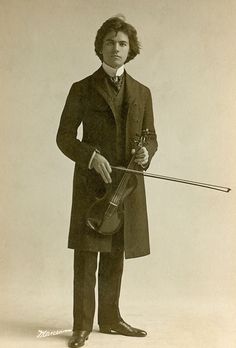 an old black and white photo of a man holding a violin