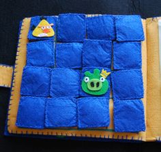 a blue and yellow patchwork case with angry birds on it's side, sitting on a black surface