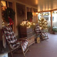 two rocking chairs on the front porch decorated with christmas lights and plaid blankets, surrounded by potted trees