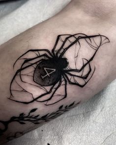 a black and white spider tattoo on the arm