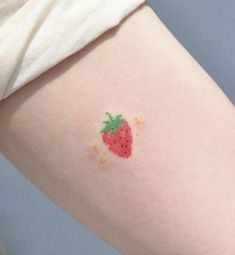 a small strawberry tattoo on the left thigh and right leg, with sprinkles all over it