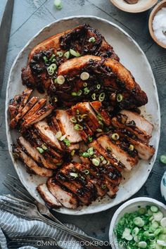 grilled chicken with sauce and green onions on a white plate next to other dishes