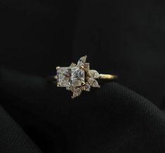 an engagement ring with three stones on it, sitting on top of a black cloth