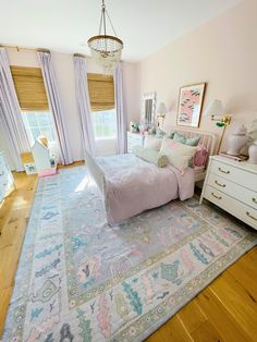 a bedroom with pink walls, white furniture and a large rug on the wooden floor