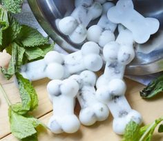 some mint leaves and white dog bones on a wooden table