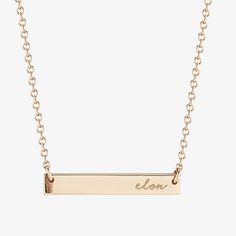 a gold bar necklace with the word lon on it's front and back