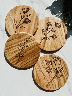 four wooden coasters with etched flowers on them