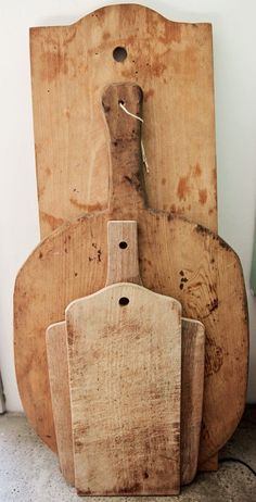 three wooden cutting boards sitting next to each other on top of a floor near a wall