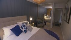 a bedroom with blue walls and white bedding