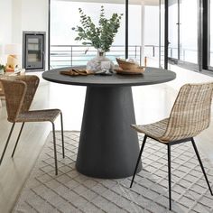 a round table with two chairs and a vase on it in the middle of a room