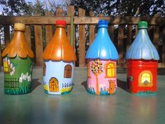 three colorful painted plastic bottles sitting on top of a wooden table next to a fence