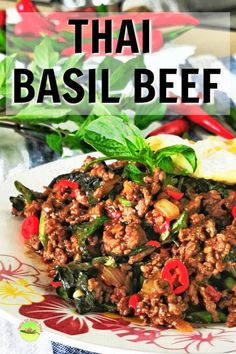 thai basil beef on a white plate with red peppers and green leaves in the background