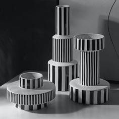 three black and white striped vases sitting next to each other on top of a table