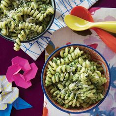 two bowls filled with pasta and broccoli sitting on top of a table next to origami flowers