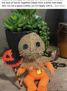 an orange doll sitting on top of a wooden table next to a potted plant