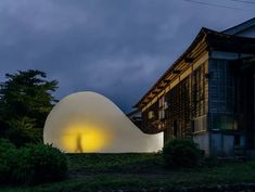 a large white object sitting in the middle of a lush green field next to a building