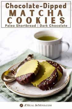 chocolate - dipped matcha cookies on a plate with a cup of tea in the background