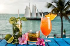 two drinks are sitting on a table next to the ocean