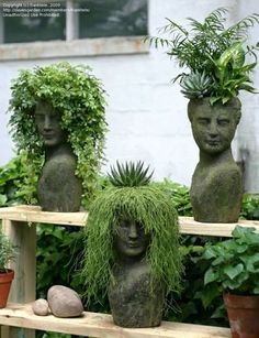 three stone statues with plants growing out of their heads in front of a window sill