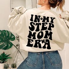 In My Stepmom Era Sweatshirt *please note this sweatshirt features a back design only.  Our Gildan 1800 sweatshirt fits true to size. This shirt has a unisex fit, nice fit on women, but men should SIZE UP at least one size.  Other details  .* 8.0 oz., 50/50 cotton/polyester  * Pre-shrunk  * Classic fit  * Reduced pilling and softer air-jet spun yarn  * 1x1 athletic rib knit collar, cuffs and waistband, with spandex  * Double-needle stitched collar, shoulders, armholes, cuffs and waistband If you Aesthetic T Shirts, Funny Mom Shirts, Soft Air, Mama Shirts, Step Moms, Mama Shirt, Mom Outfits, Mom Humor, Best Mom