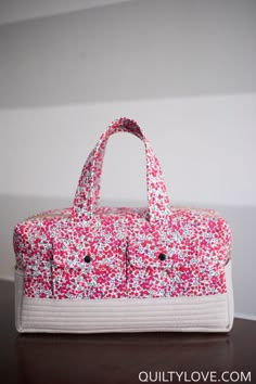 a pink and white purse sitting on top of a wooden table