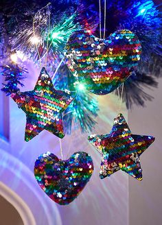 christmas ornaments hanging from a tree with lights on them and sequins in the shape of stars