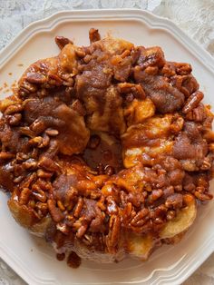 a bundt cake covered in pecans on a white plate