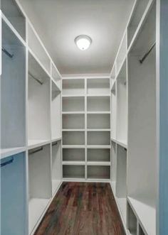 an empty walk - in closet with white shelves and wood flooring on the side