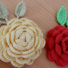 two crocheted flowers sitting on top of a wooden table