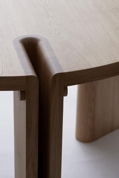 two curved wooden tables sitting next to each other on a white surface with light colored wood