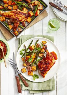 a white plate topped with meat and veggies next to a pan of food