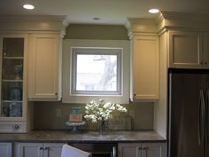 a kitchen with white cabinets and a silver refrigerator freezer sitting next to a window