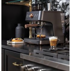 an espresso machine sitting on top of a counter next to a plate of food