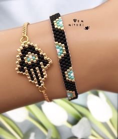 a woman's arm with two bracelets on it, one in gold and the other in black