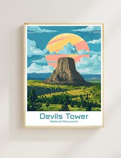 the devils tower national monument is featured in this retro style travel poster, framed on a wall