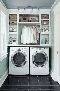 a washer and dryer in a laundry room with blue walls, black tile flooring and white cabinets