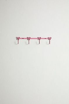 three hooks are hanging on the wall and one is holding two pairs of pink scissors