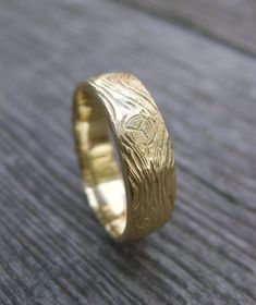 a gold wedding ring on top of a wooden table