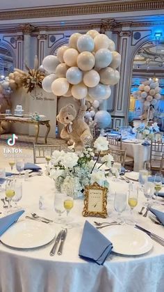 the table is set with silver and white plates, silver napkins, and balloons