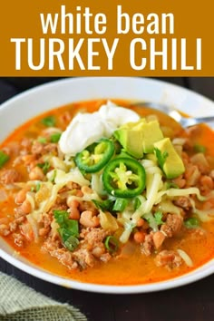 white bean and turkey chili in a bowl with sour cream, green onions, jalapenos