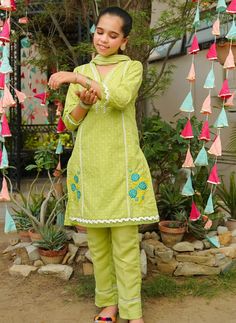 3- Piece Embroidered Suit for Girls This light leafy green chikankaari kameez is finished off with white laces and a beautiful floral embroidered motif on the daman in the shades of blue and yellow. Accompanied with a matching light green cotton trouser trimmed with laces and a contrasting light blue crush dupatta, this fun new color way is the perfect combination of style and design for the current season. Description : Top: Lime Green Chikankari Kurta with Embroidery and Laces Bottom: Lime Gre Spring Cotton Salwar Kameez With Dabka, Fitted Cotton Churidar For Spring, Green Cotton Churidar For Traditional Events, Spring Yellow Embroidered Lawn Suit, Pista Green Dresses With Dabka Work For Spring, Spring Cotton Salwar Kameez With Dabka Detailing, Spring Cotton Churidar With Dabka Work, Yellow Chikankari Salwar Kameez For Spring, Spring Cotton Churidar With Chikankari Embroidery