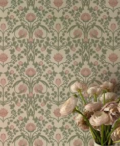 a vase filled with flowers sitting on top of a table next to a wall paper