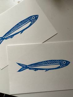 three cards with blue fish on them sitting on top of a table next to each other