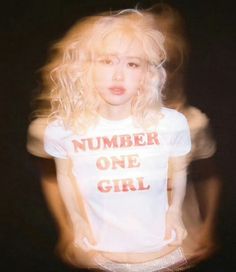 a woman with blonde hair wearing a white t - shirt that says number one girl